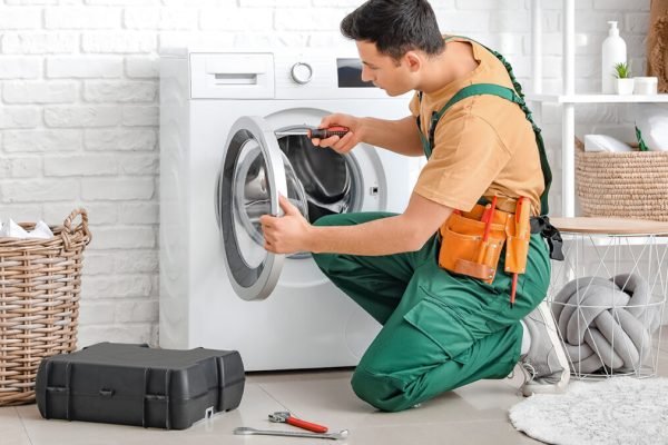 Worker repairing washing machine in laundry room